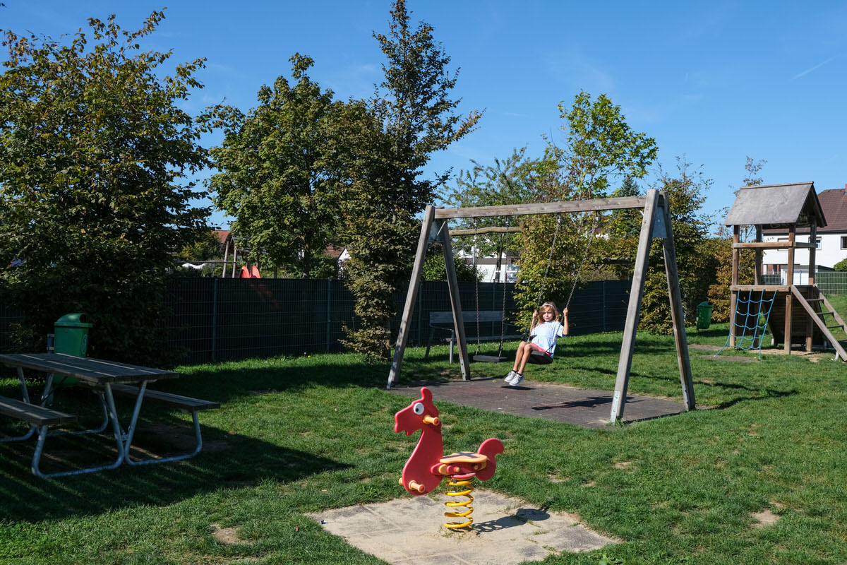 Spielplatz mit Schaukelpferd, Schaukel und Bänken