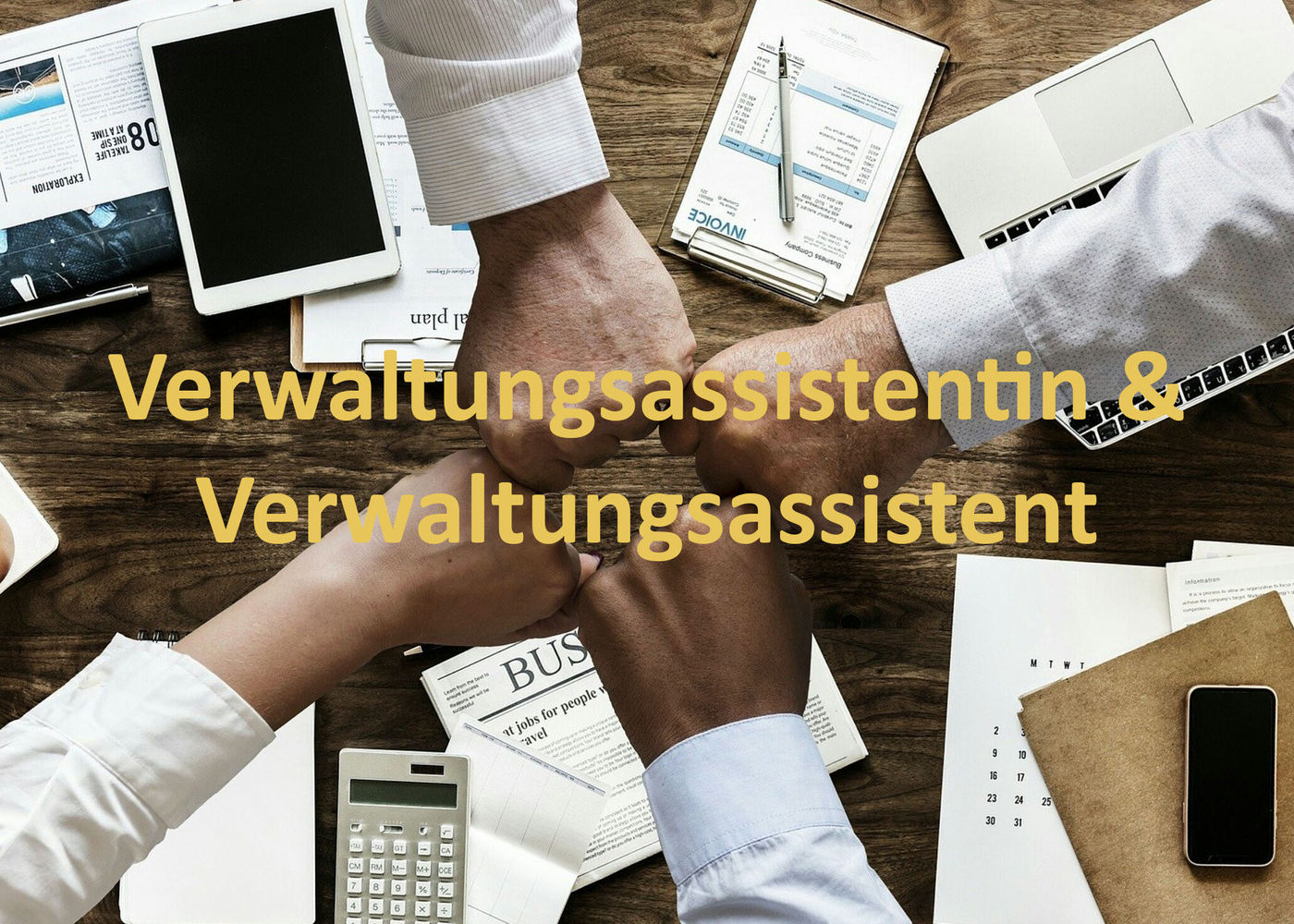 4 Fäuste treffen in der Mitte zusammen, Hintergrund Holzplatte mit diversen Büromaterialien