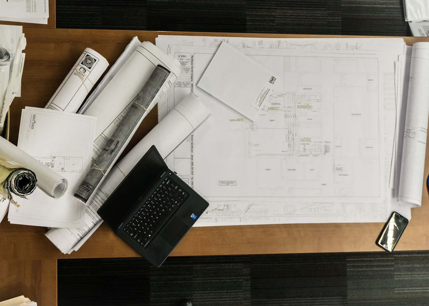 Arbeitsplatz mit diversen Plänen und einem Laptop
