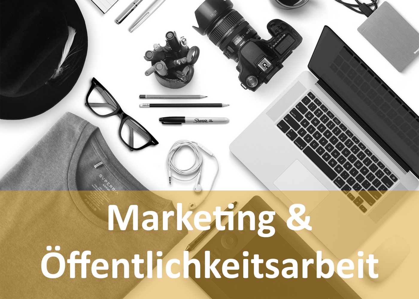 Kamera, Stifte, Brille, Kopfhörer, Laptop, Tablet, T-Shirt, Hut auf weißen Untergrund liegend