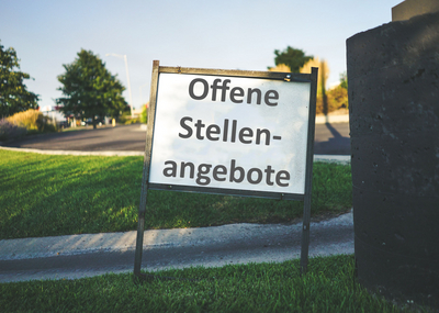 Hintergrund Straße und Wiese, Vordergrund Tafel mit Aufschrift "Offene Stellenangebote"