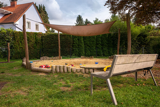 Große Sandkiste mit Sonnensegel und einer Bank